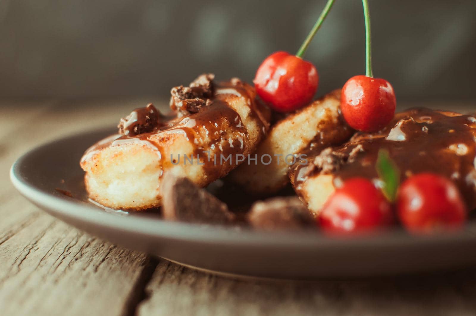 Gourmet breakfast - curd pancakes, cheesecakes, curd pancakes with cherries and chocolate in a brown plate. Wholesome dessert on a wooden table in a rustic style. Selective focus