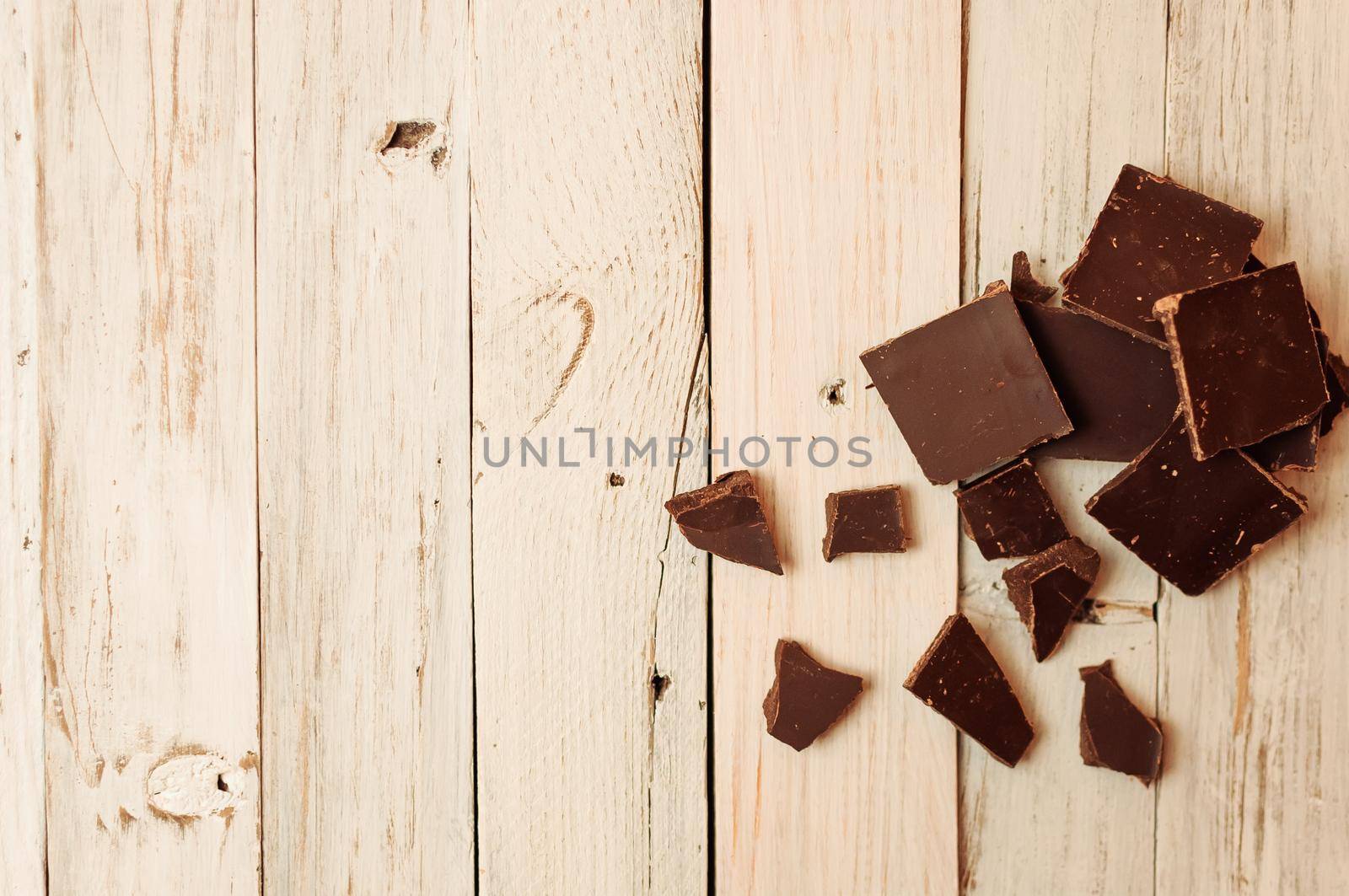 dark chocolate without sugar and gluten free for diabetics and allergics. Black chocolate broken into pieces lies on a white table in a rustic style. Copy space.
