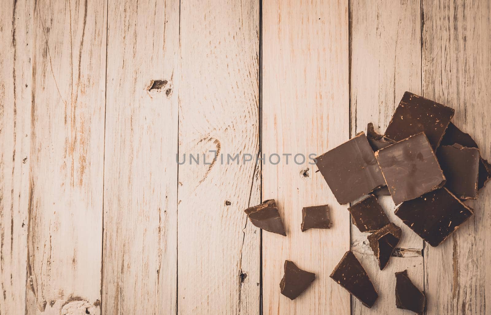 dark chocolate without sugar and gluten free for diabetics and allergics. Black chocolate broken into pieces lies on a white painted table in a rustic style. Dark toning. Copy space.