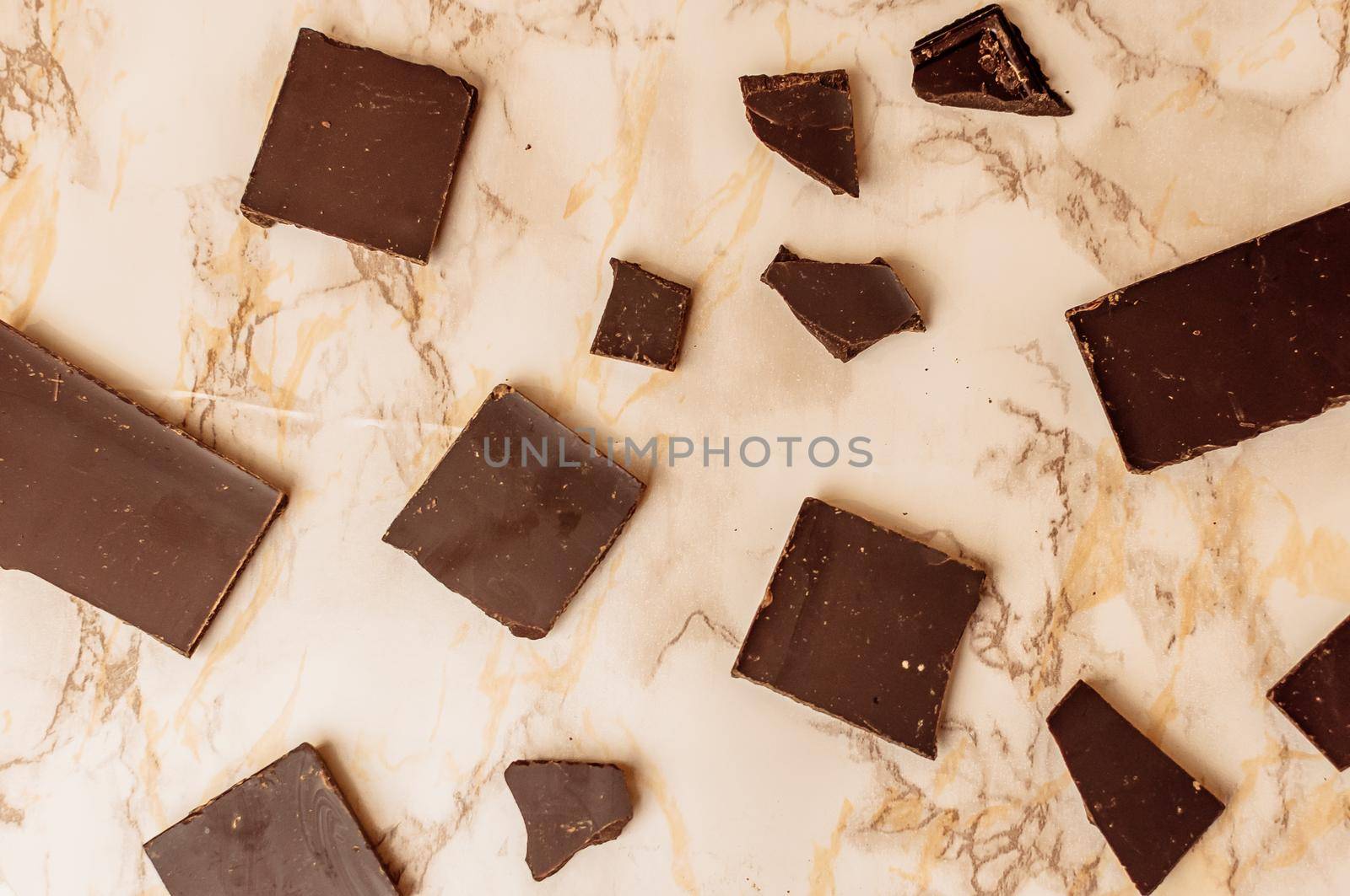 dark chocolate without sugar and gluten free for diabetics and allergics. Pieces of chocolate lie on a marble table.Pattern from chocolate slices