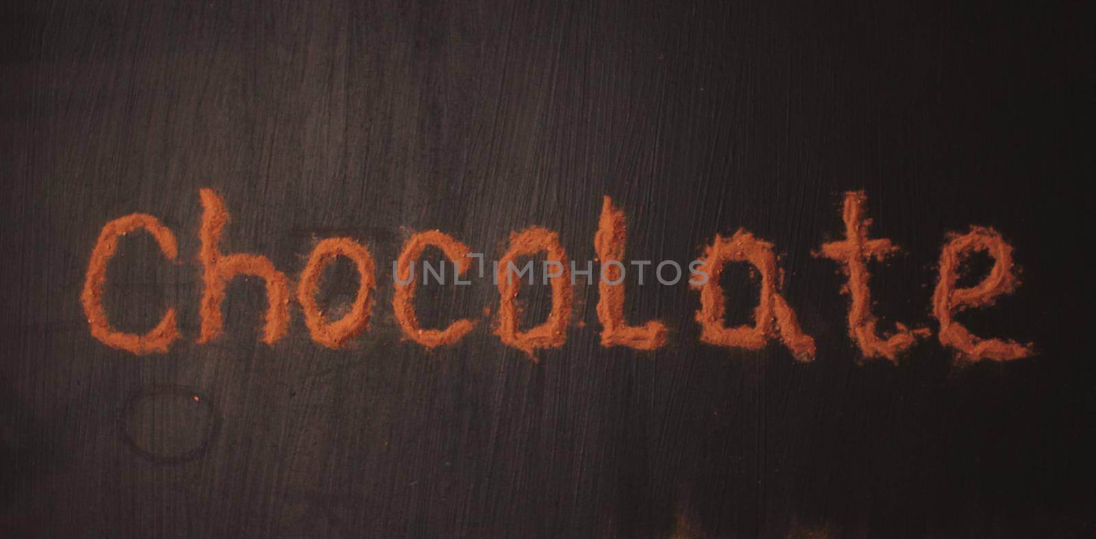 inscription chocolate made by cocoa powder on a black graphite background