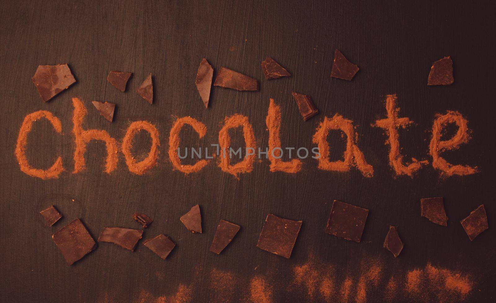 inscription chocolate made with cocoa powder with the addition of pieces of chocolate on a black graphite background