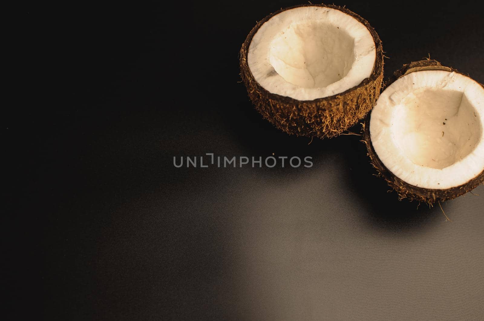 ugly organic coconut on a black background, isolate. a broken nut in a shell the white insides of a coconut, which began to decompose and covered with fungus and mold. Spoiled products. Copy space.