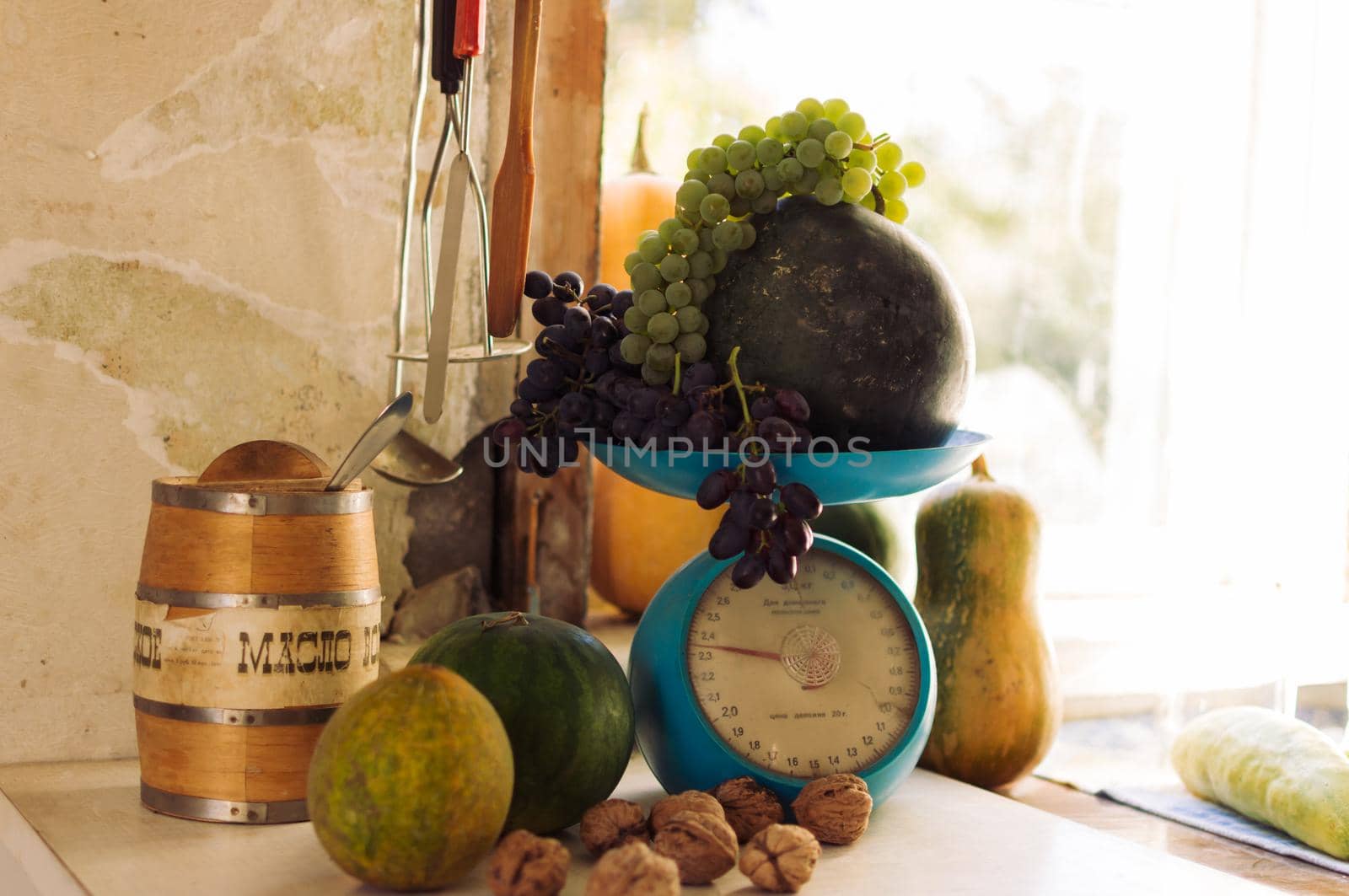 Autumn still life with pumpkins,walnuts,melons,watermelon and grapes on scale to scale and on a wooden white table. Autumn harvest concept. Happy Thanksgiving. Selective focus. Horizontal orientation.