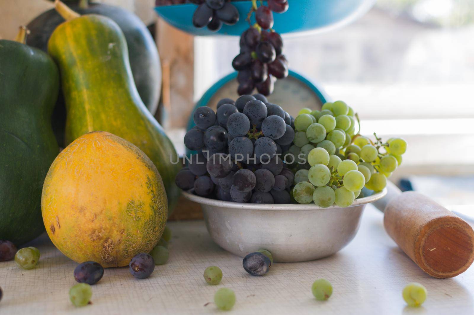 Autumn still life with pumpkins, melons, watermelon, grapes on a scale and in a metal bowl on a wooden white table. Autumn harvest concept. Happy Thanksgiving. Selective focus. Template for design.