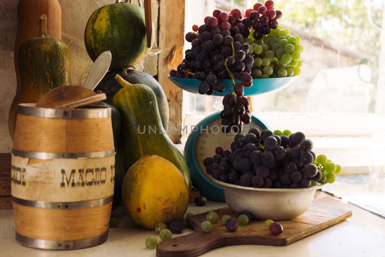 Autumn still life with pumpkins, melons, watermelon, grapes on a scale and in a metal bowl on a wooden white table. Autumn harvest concept. Happy Thanksgiving. Selective focus. Template for design.