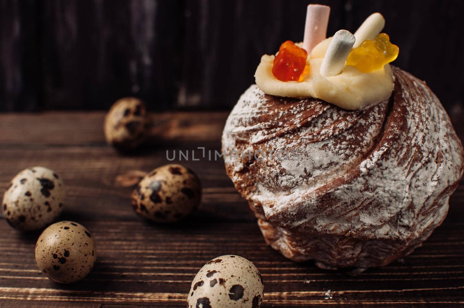 Stylish Easter cake with marshmallows and jelly bears on dark rustic wooden background,quail eggs lie nearby.Seasonal Greetings Happy Easter. place for text. Selective focus. modern happy easter image