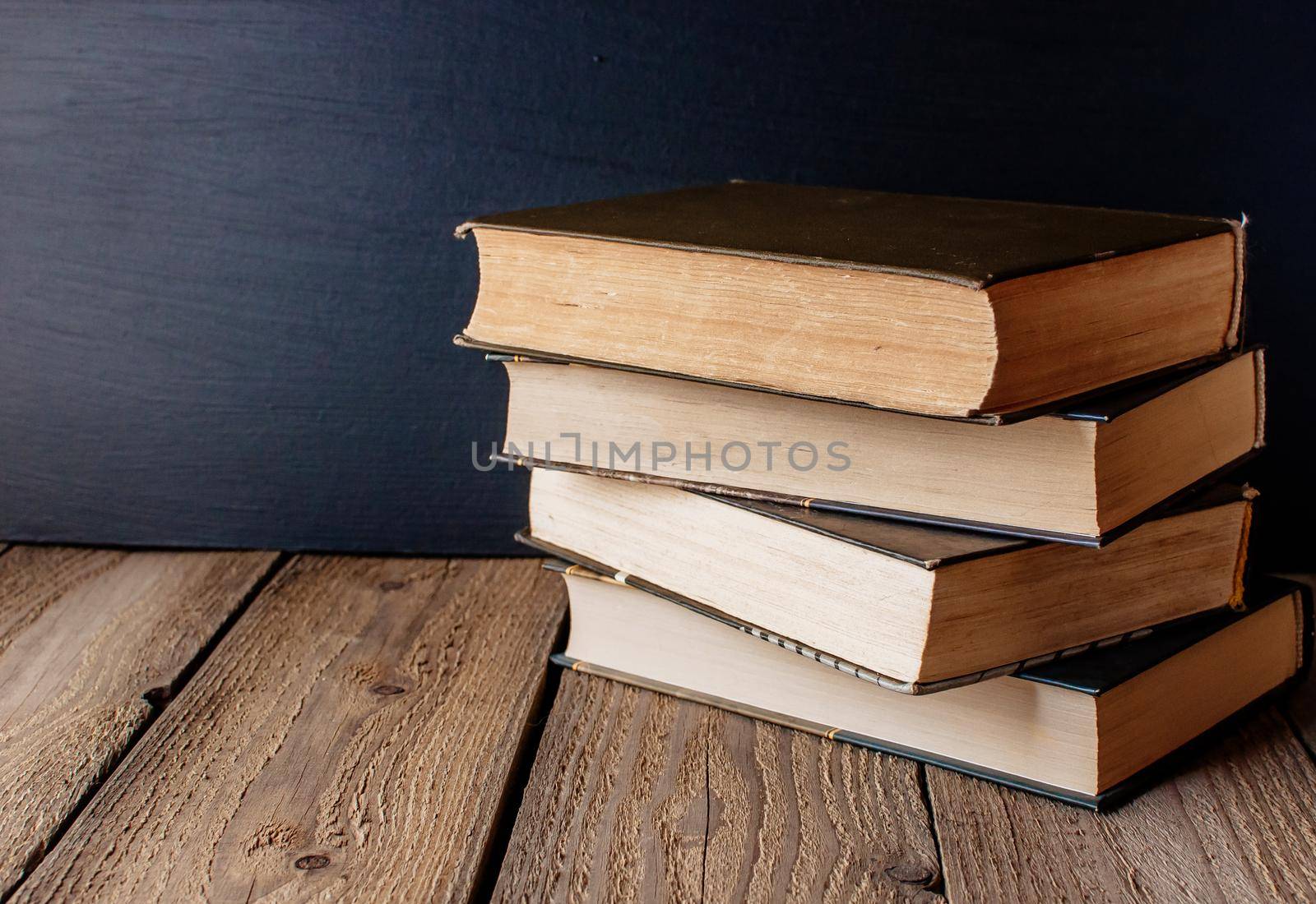 books stacked on a wooden table in a rustic style on the background a school blackboard. The concept of welcome back to school. copy space