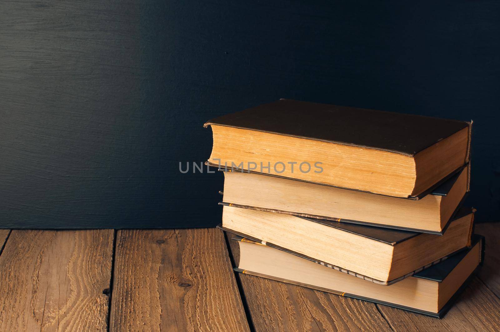 books stacked on a wooden table in a rustic style on the background a school blackboard. The concept of welcome back to school. copy space by Alla_Morozova93