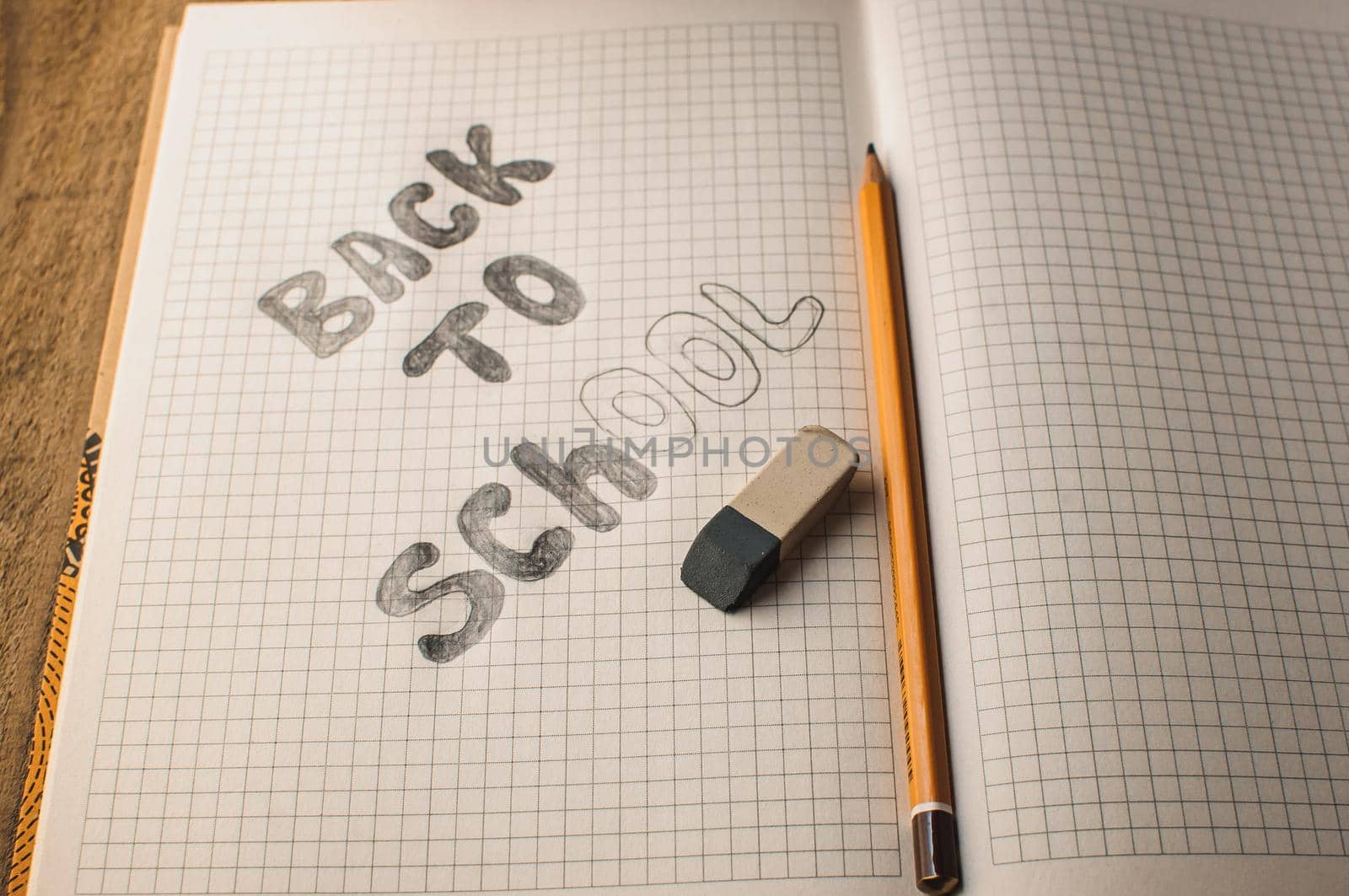 Back to school, the concept of raising children. Day of knowledge. Notebook in a slanting line on a wooden table with space for text. Save space. Rustic and vintage toning.