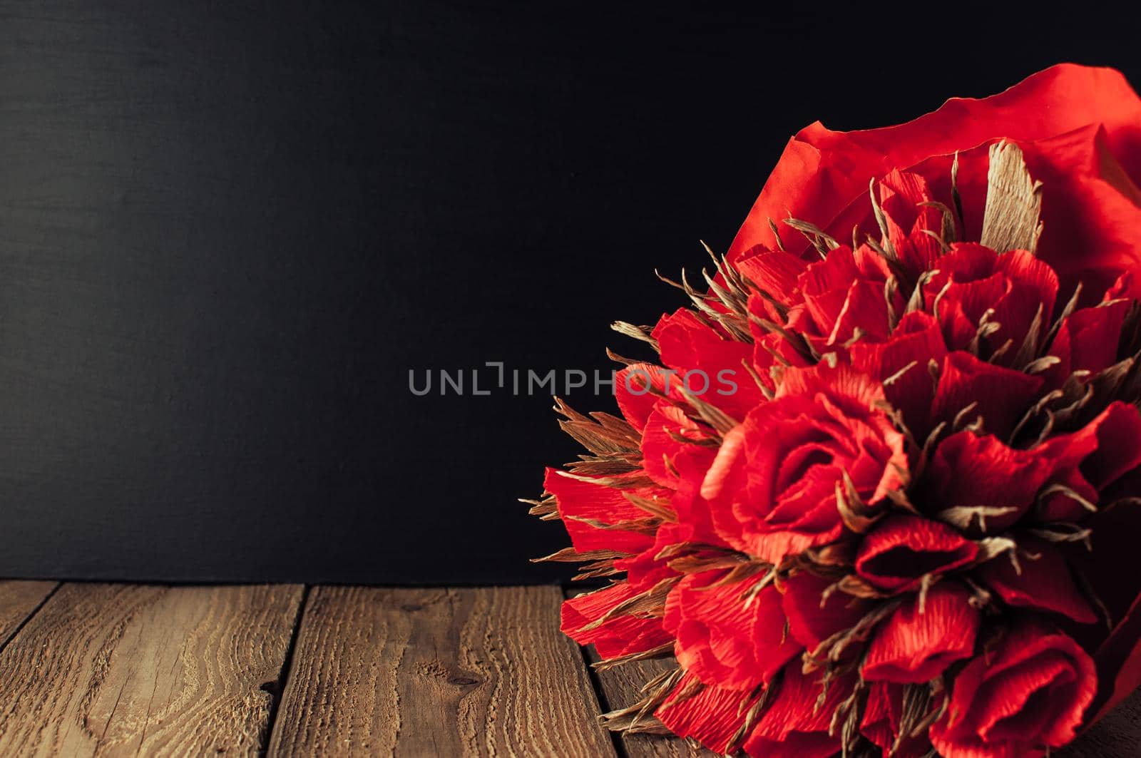 Back to school, the concept of parenting. Day of knowledge.A bouquet of roses against the background of a black school board.Education concept.Copy space. Rustic and vintage toning.