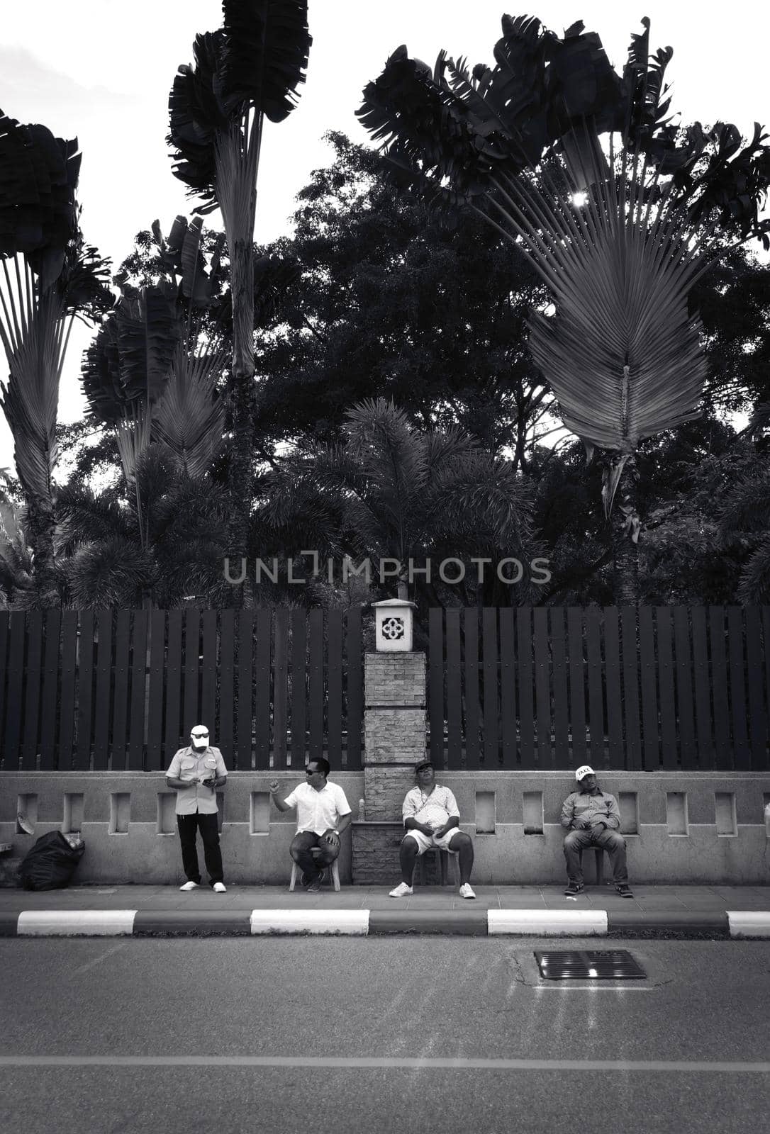 2019-11-05 / Phuket, Thailand - Four sitting men idling on the sidewalk. Black and white. by hernan_hyper