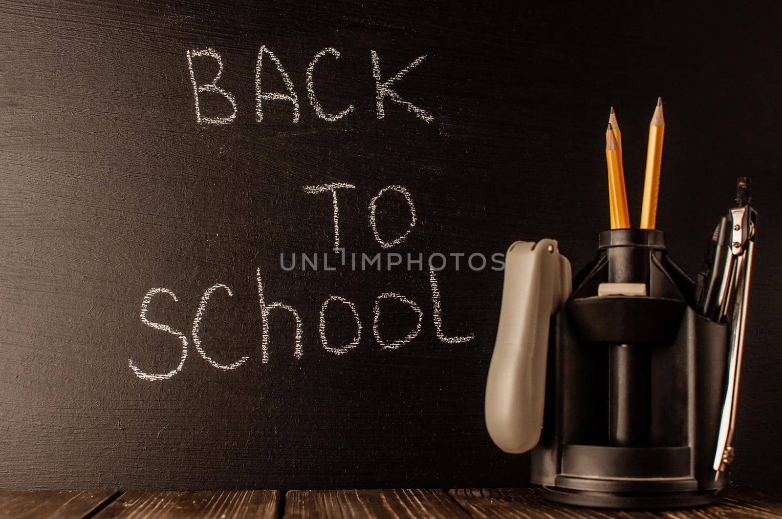 Back to school, the concept of parenting. The inscription on the blackboard with white chalk, next to it is a stand for pens with stationery. Place for text. Copy space by Alla_Morozova93