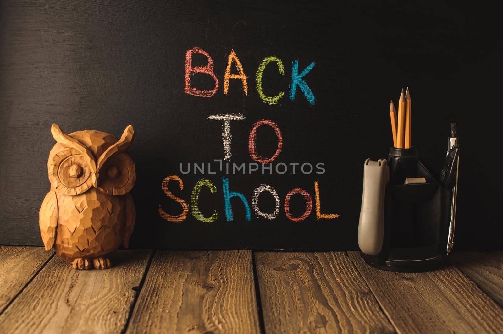 Back to school, the concept of parenting. An assortment of consumables, owl, notebook, pencils, stand for pens. The inscription on the slate black chalk. School supplies on a wooden table, rustic. by Alla_Morozova93