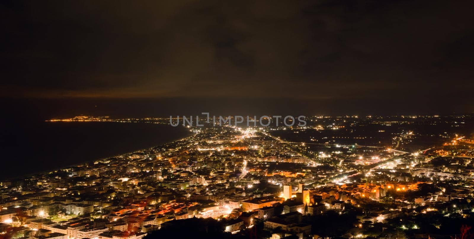 Aerial night view of the city of Terracina, Italy, by the Mediterranean sea.
