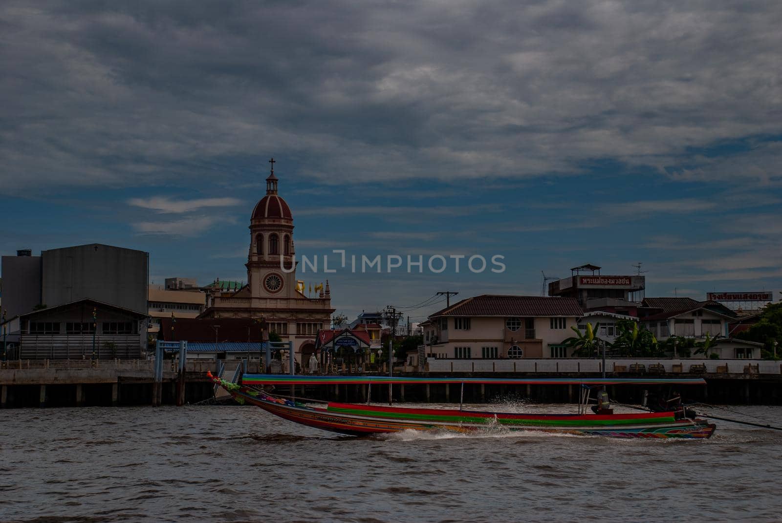 Bangkok, Thailand - 21 Jul 2019 : Long-tailed  boat rushing on water surface against of Chao Phraya  through the Santa Cruz Church in the Kingdom of Thailand.
