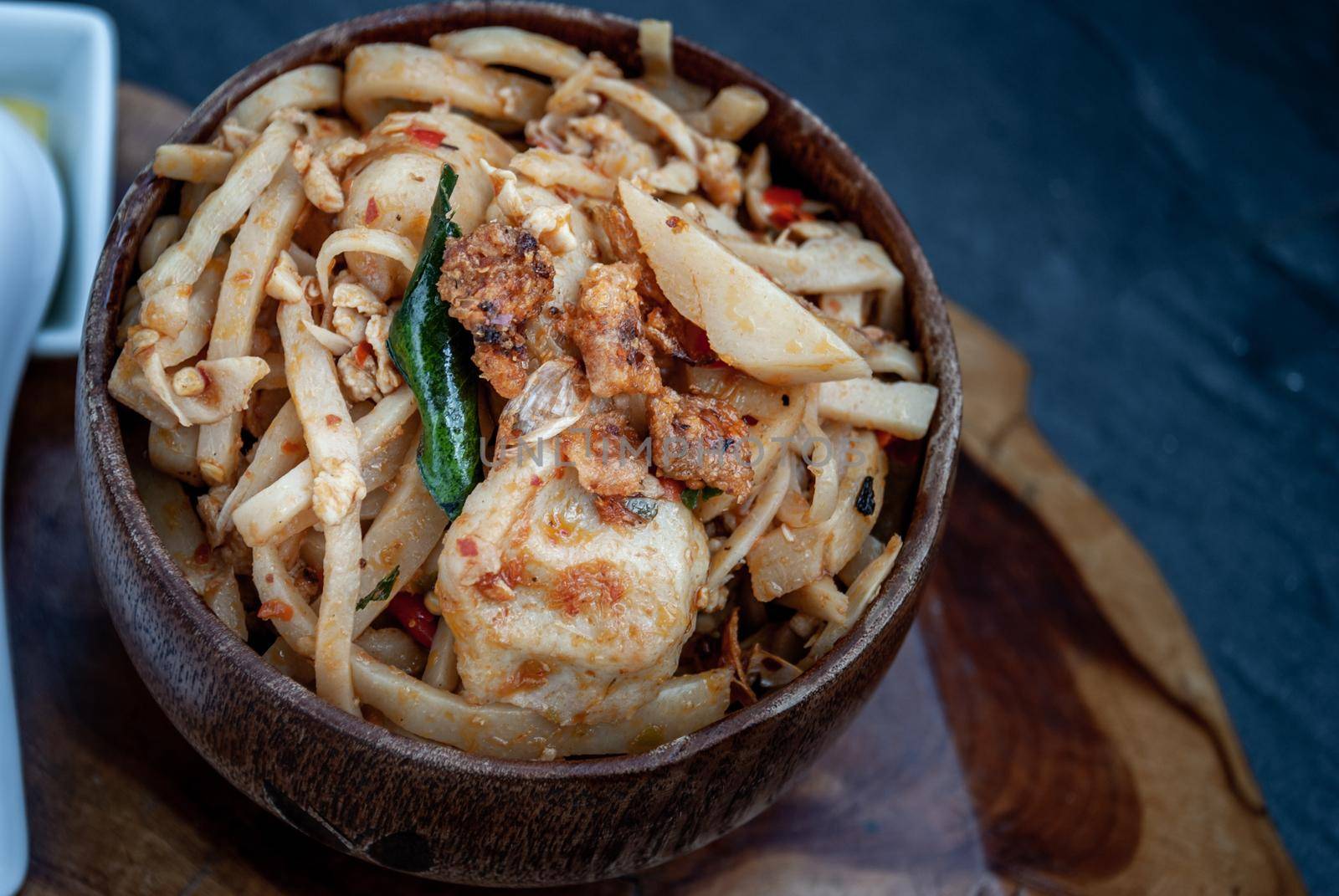 Thai food, Spicy stir fried bamboo shoot with fish ball in a wooden bowl. Oblique view from the top.