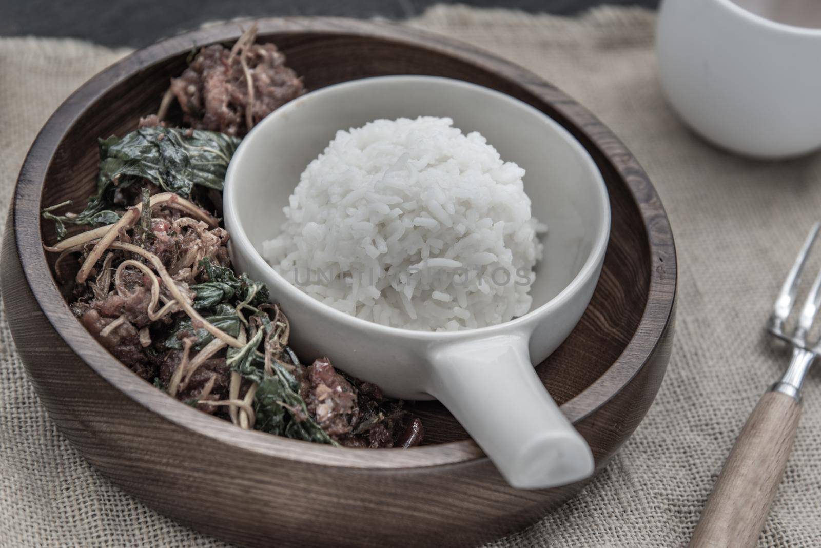 Thai Spicy food, Spicy Stir Fried Deep Fish Fillet with Herbs vegetables served with steamed rice in wooden bowl : in Thai language called "Pad Cha " Oblique view from the top, Selective focus.