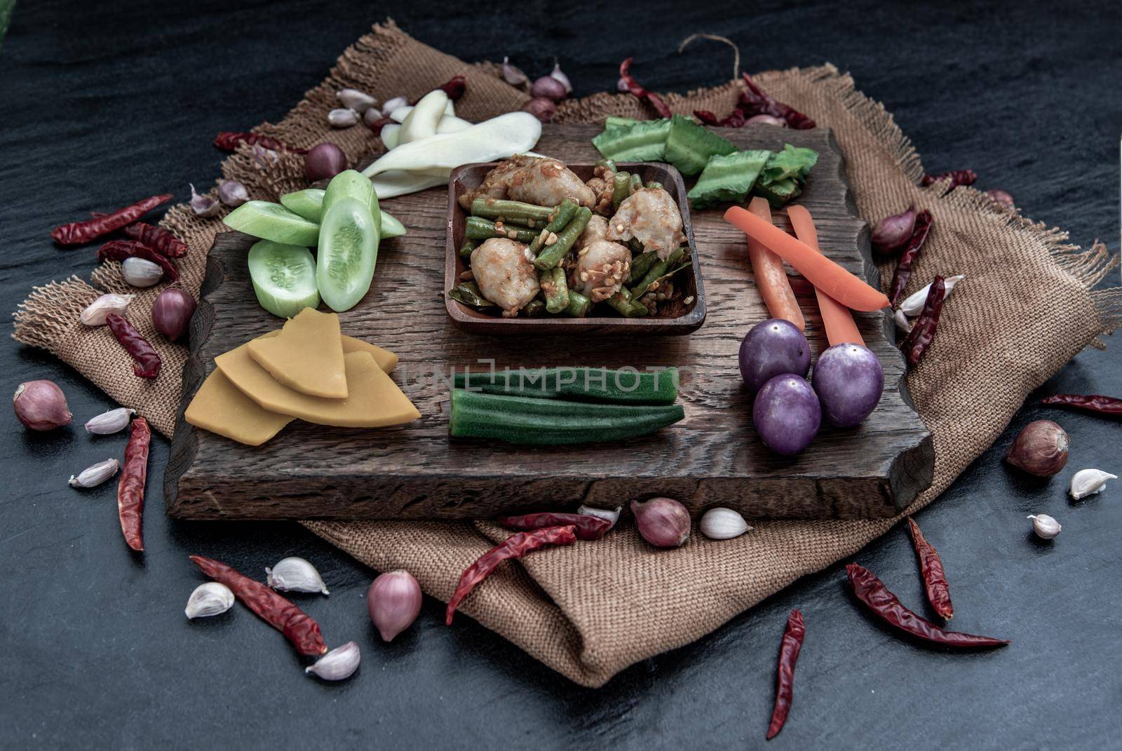 Thai food, Stir Fried fish ball with Red Curry Paste and long bean with the ingredient and fresh vegetables on wood background, Oblique view from the top.