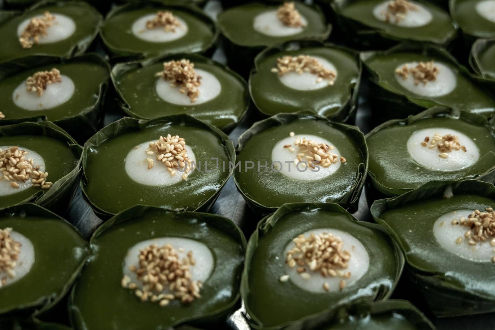 Thai Dessert Pandan Sweet Pudding (Kanom Piak Poon Bai Toey) in Sweet Coconut milk Cream with sesame seeds and Thai pudding with coconut topping, Thai dessert, Selective focus.
