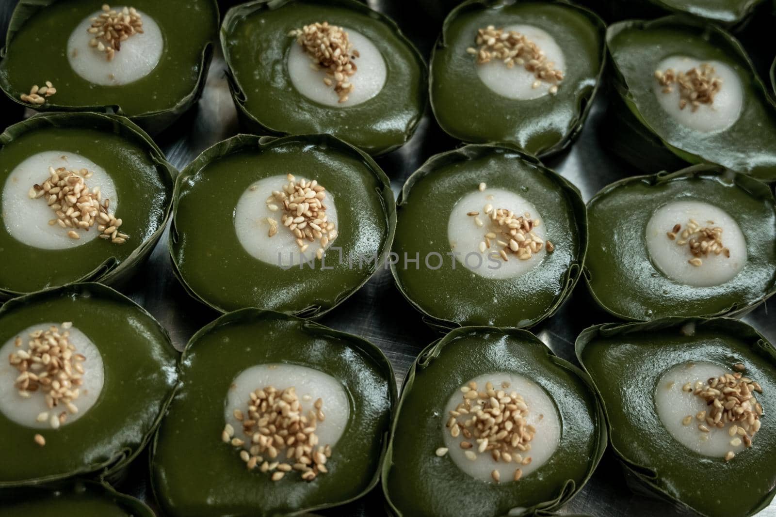 Thai Dessert Pandan Sweet Pudding (Kanom Piak Poon Bai Toey) in Sweet Coconut milk Cream with sesame seeds and Thai pudding with coconut topping, Thai dessert, Selective focus.
