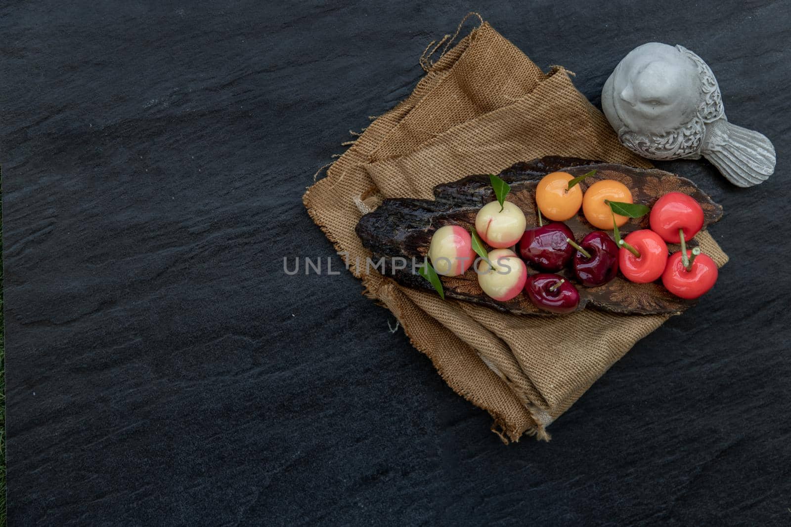 Kanom Look Choup : An old traditional thai dessert made from green been, coconut milk, sugar and jelly, Deletable imitation fruits made from green been, coconut milk, sugar and jelly in fruit shape on wooden, It is a unique dessert of Thailand, Top view.
