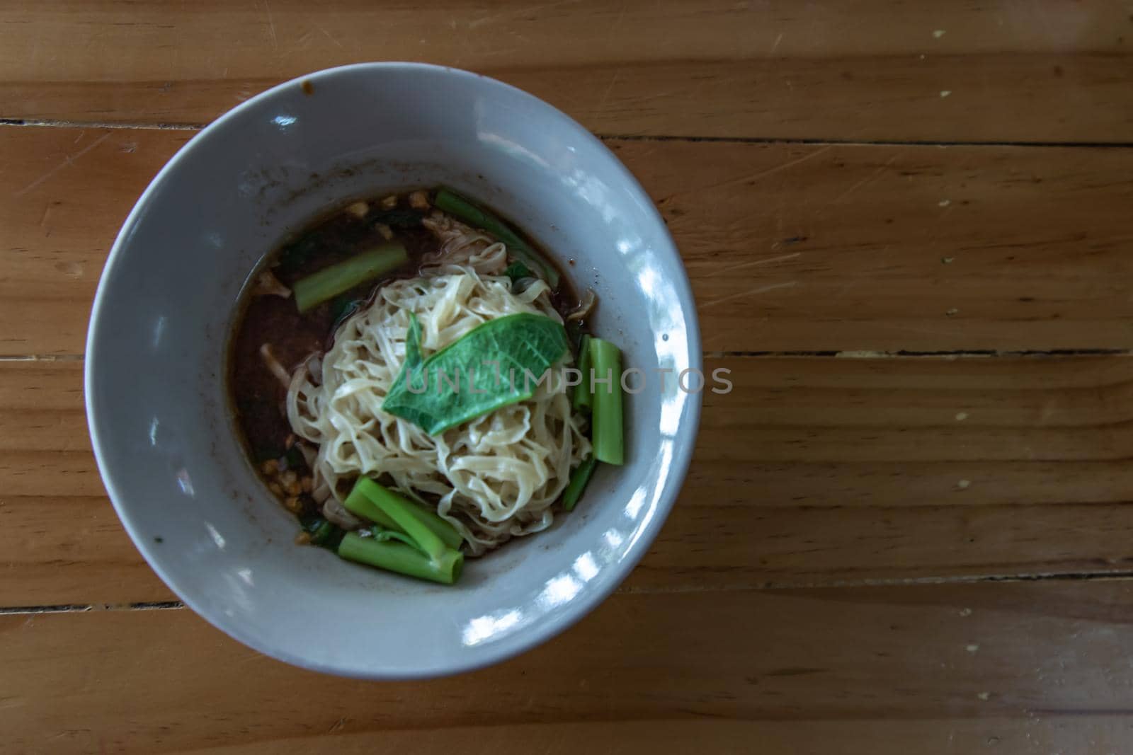 Thai boat noodle soup (Kuaytiaw reua) This delicious Thai noodle soup Local food in Thailand that can be eaten in general is delicious and cheap, Braised pork noodles on the wooden table. Local street food in Thailand, Boat culture noodles style with copy space, Selective focus.