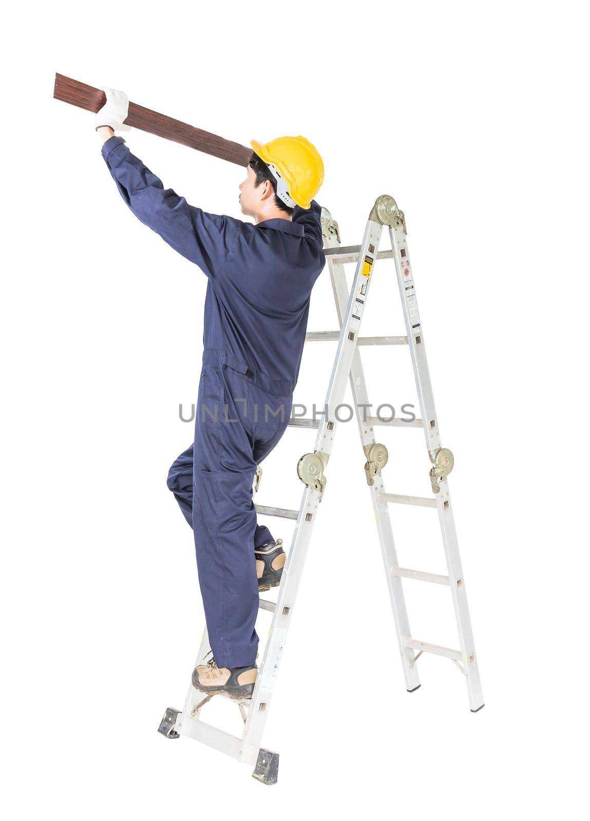 Young handyman in uniform standing on ladder construction holding wood plank on white, Cutout isolated on white background