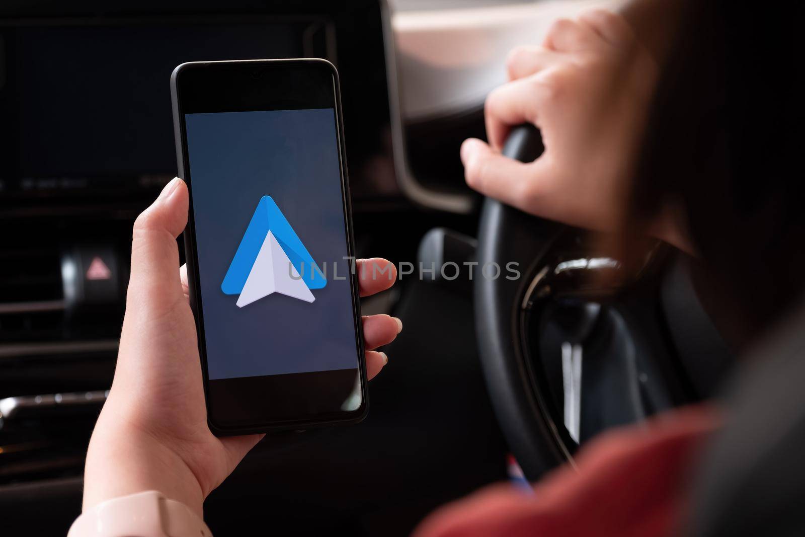 CHIANG MAI , THAILAND - MAR 28, 2021: Close up to female driving and using navigation appliction Google Android Auto. An illustrative editorial image. by nateemee