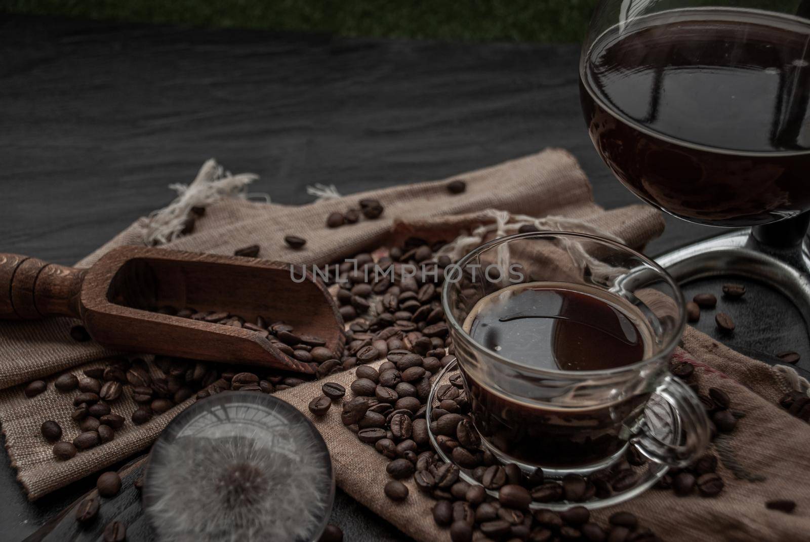 Coffee style, Cup of coffee and coffee beans roating with old wooden scoop and coffee beans around on the wooden and dark stone background. Oblique view from the top with copy space for your text, Selective focus.