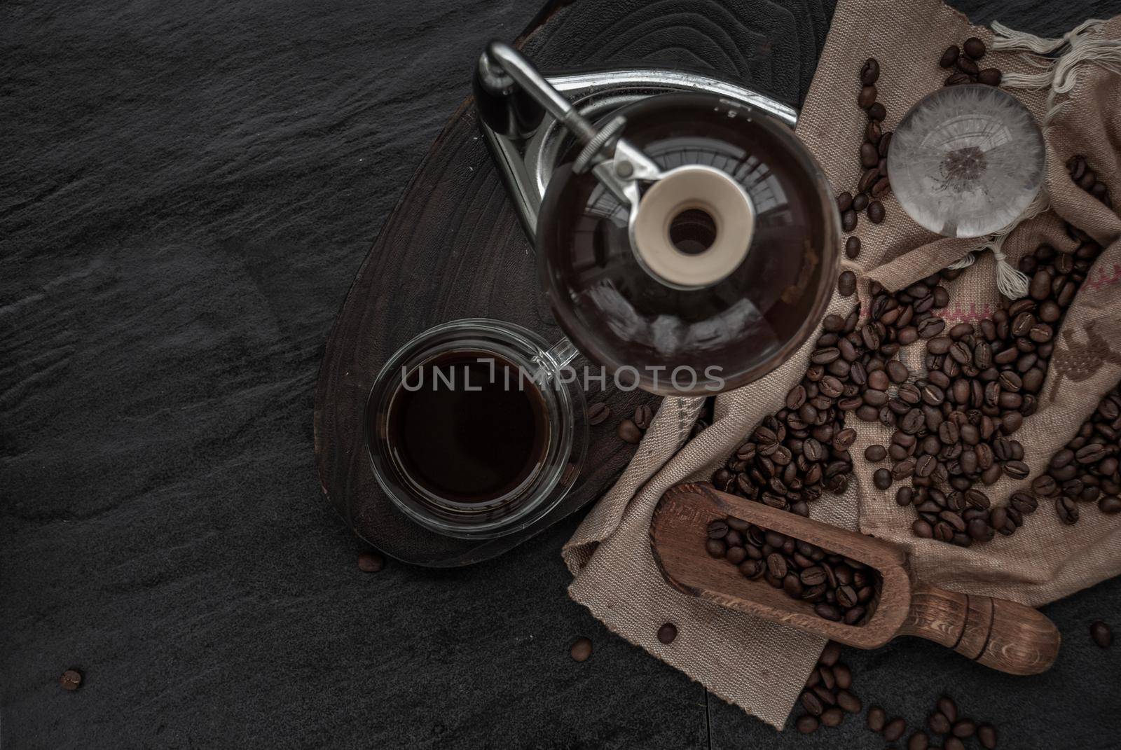 Coffee style, Cup of coffee and coffee beans roating with old wooden scoop and coffee beans around on the wooden and dark stone background. Top view with copy space for your text.