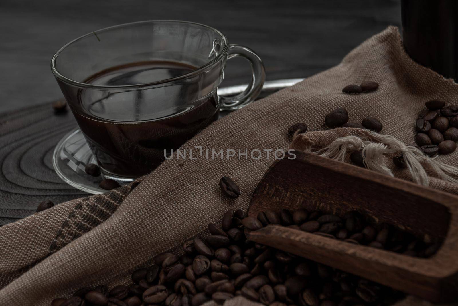 Coffee style, Cup of coffee and coffee beans roating with old wooden scoop and coffee beans around on the wooden and dark stone background. Close-up.