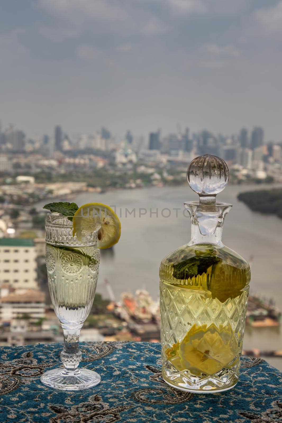 Cold water with lemon, kaffir lime, cucumber and mint leave on the table in front of sky background. Summer time, Healthy drink, vegetable juice, Selective Focus.