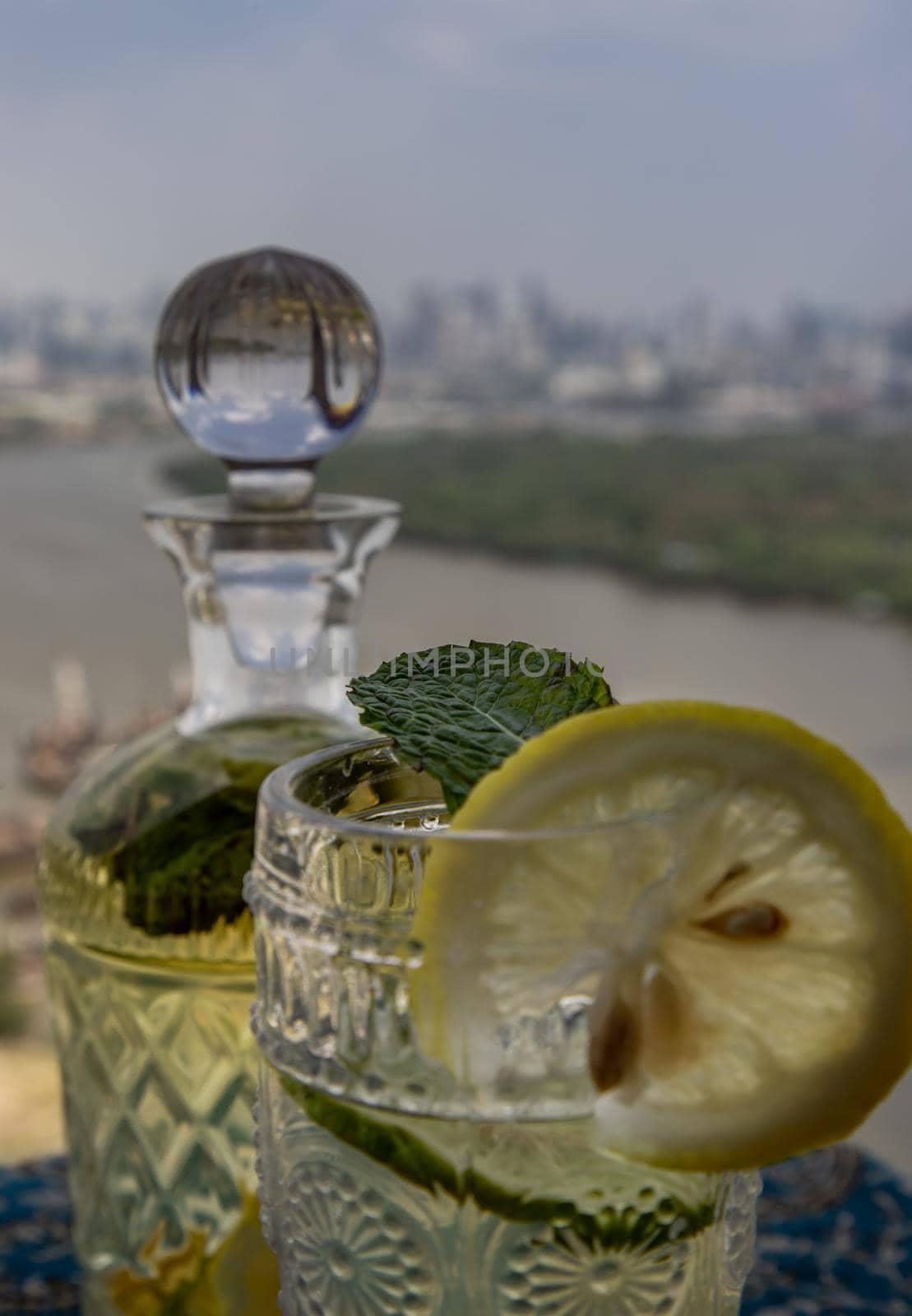 Cold water with lemon, kaffir lime, cucumber and mint leave on the table in front of sky background. Summer time, Healthy drink, vegetable juice, Selective Focus.