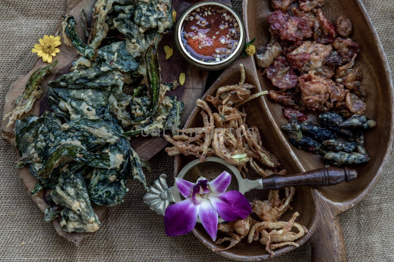 Close-up of Crispy Flowers, Crispy Herbs and Crispy Vegetables served  with Sweet sauce in a Wooden tray, copy space.