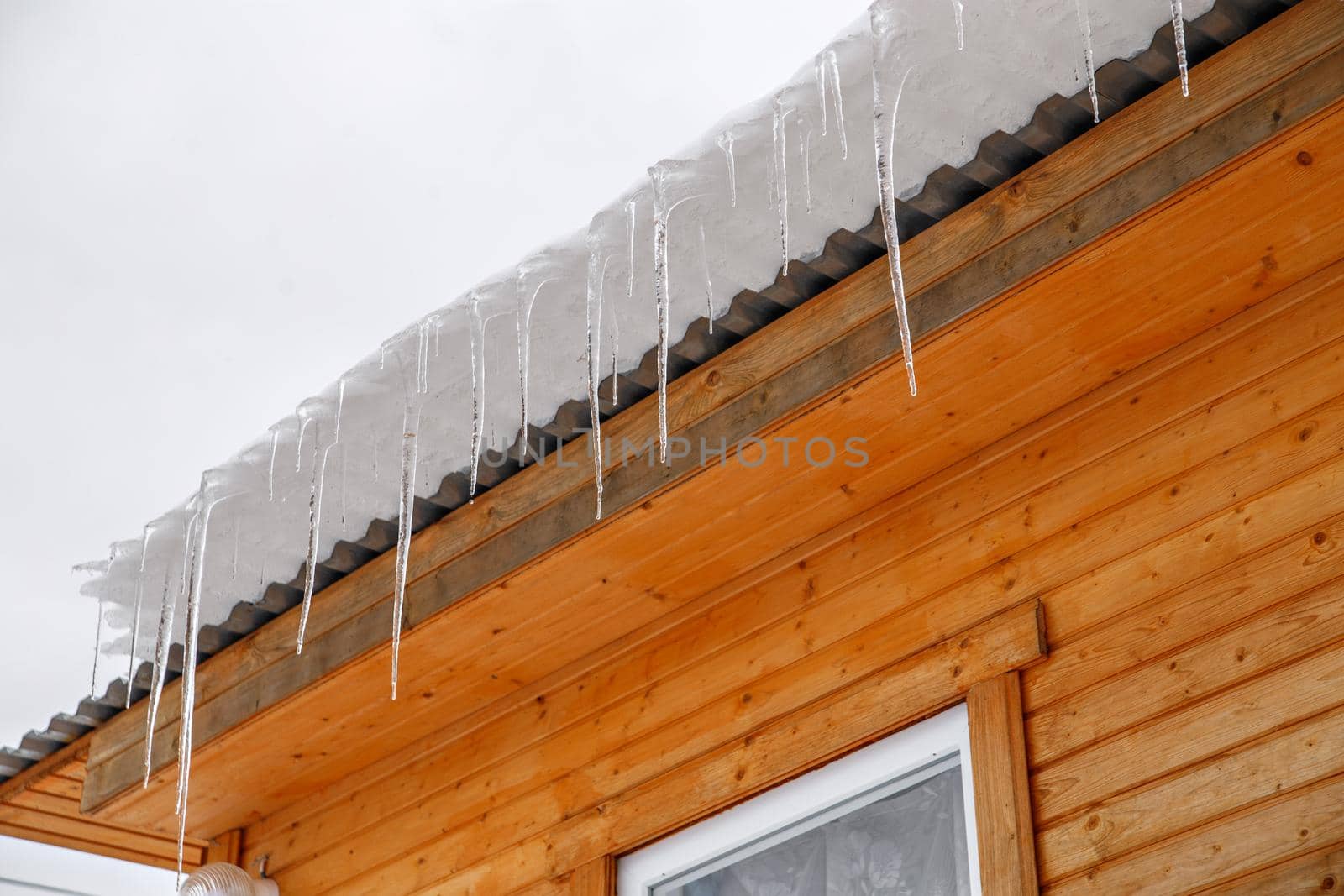 Spring ice icicles on roof of house. Patterns scattered by sun and frost. Selective focus