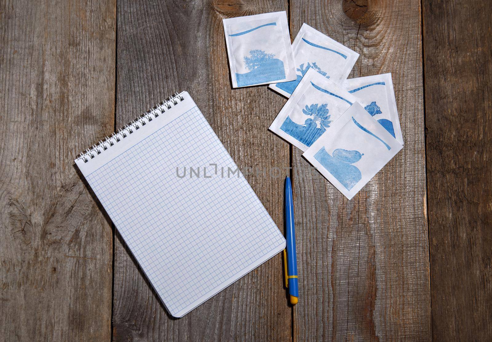 Packages of seeds, notebook and pen lie on wooden surface.