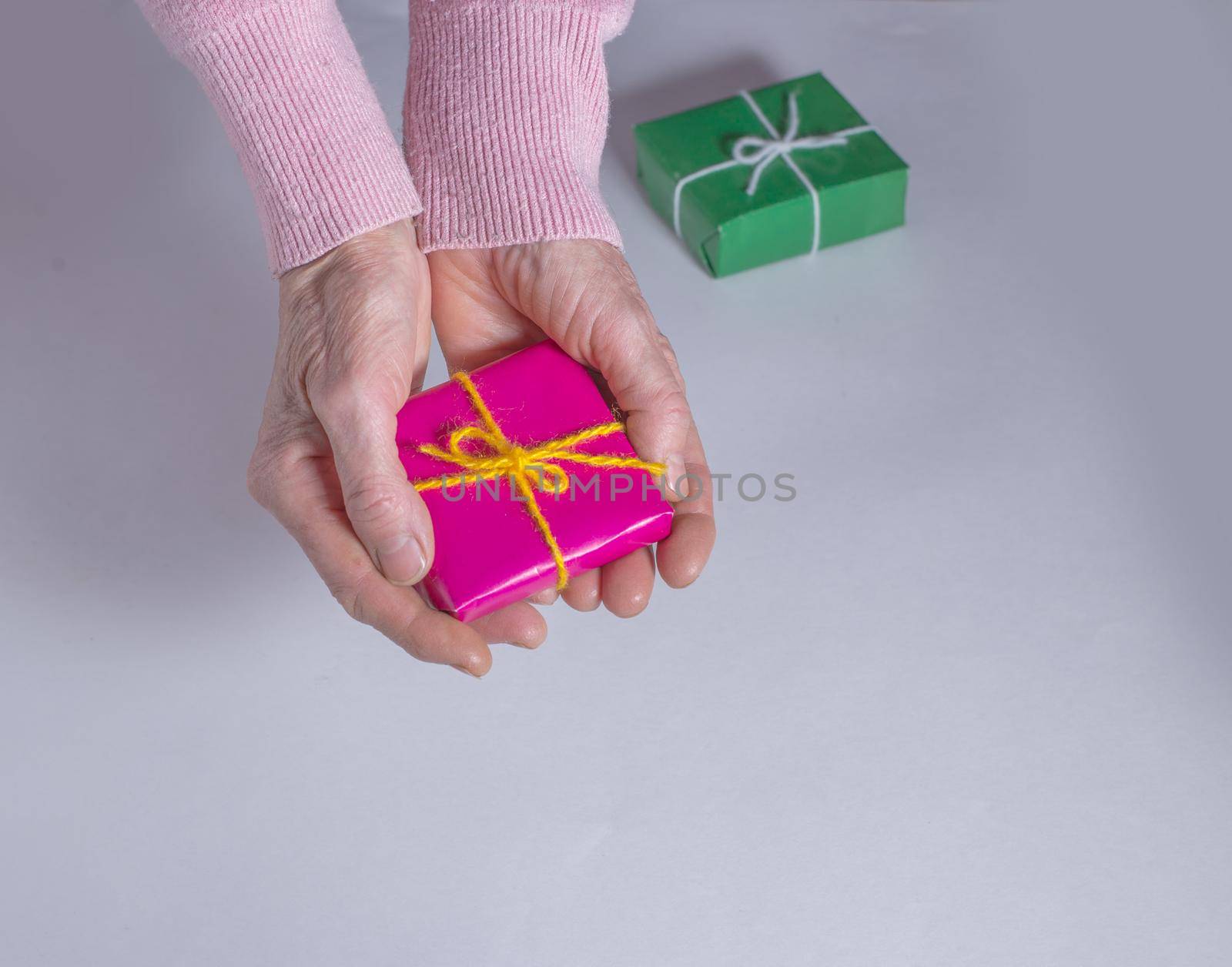 Red box in hands and green box on table. Gifts.