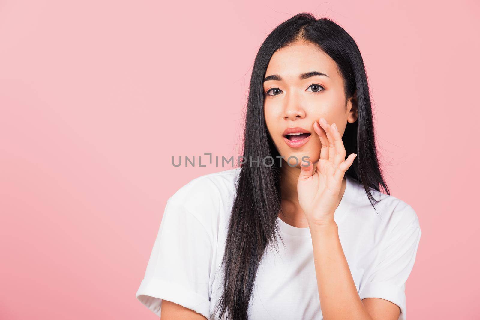Asian happy portrait beautiful cute young woman teen standing hand on mouth talking whisper secret rumor studio shot isolated on pink background, Thai female looking to camera with copy space