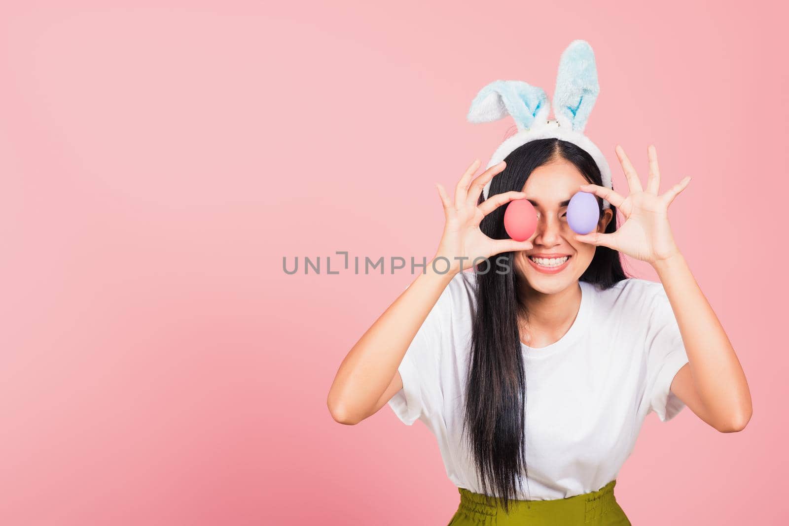 woman smiling wearing rabbit ears holding colorful Easter eggs front eyes by Sorapop