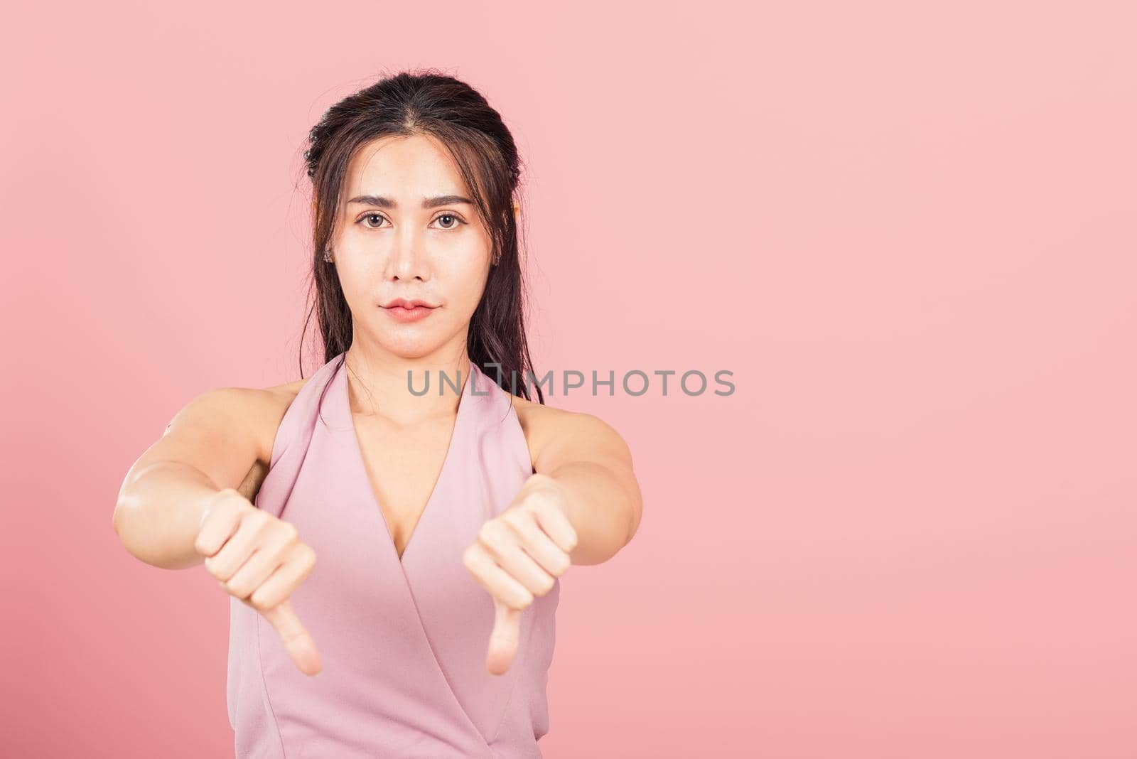 woman unhappy, negative gesture showing finger thumbs down by Sorapop