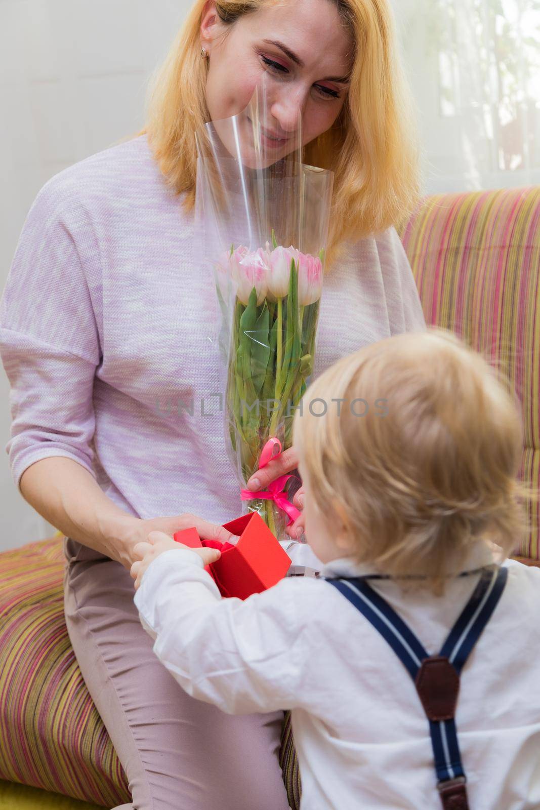 The kid congratulates his mother on the holiday, gives her flowers and a gift. by Yurich32