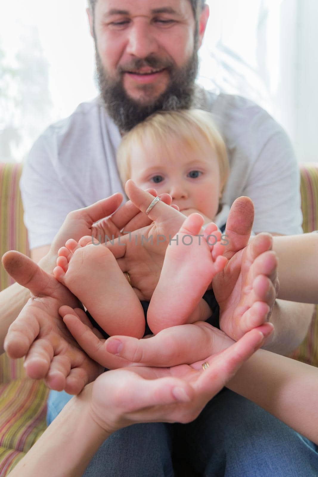 Parents and children hold the baby's heels in the palms of their hands. by Yurich32