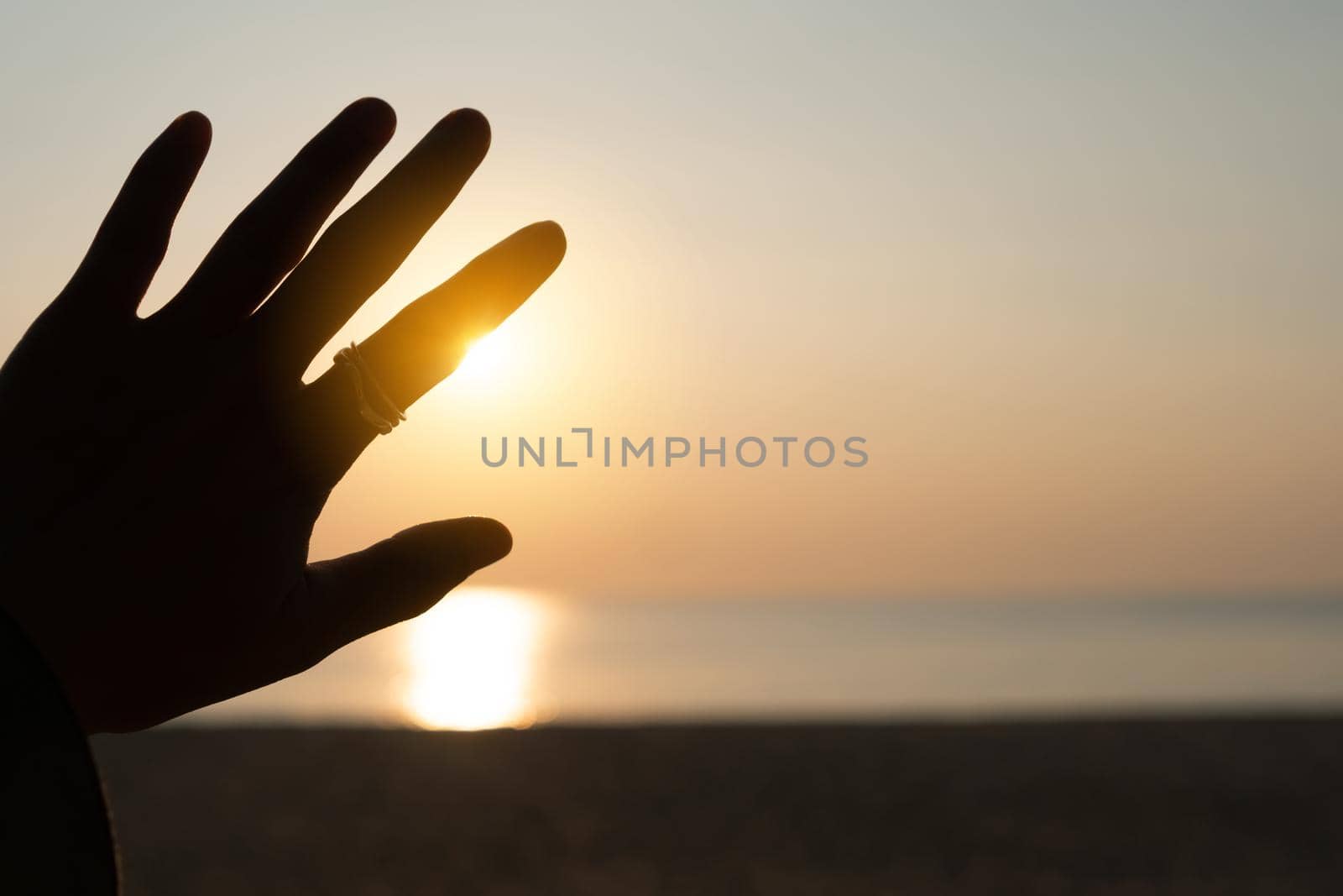 Hand reach out to sunset sky beach sand nature background. Relax and rest in vacation time.