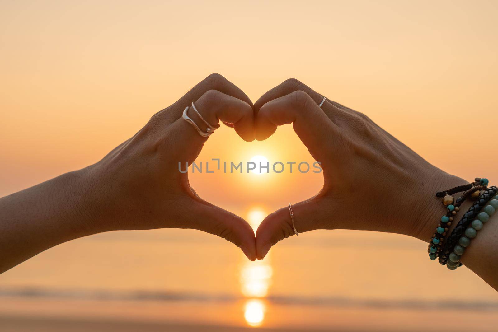 Woman hand do heart shape on sunset sky and bokeh background. love valentine day concept.