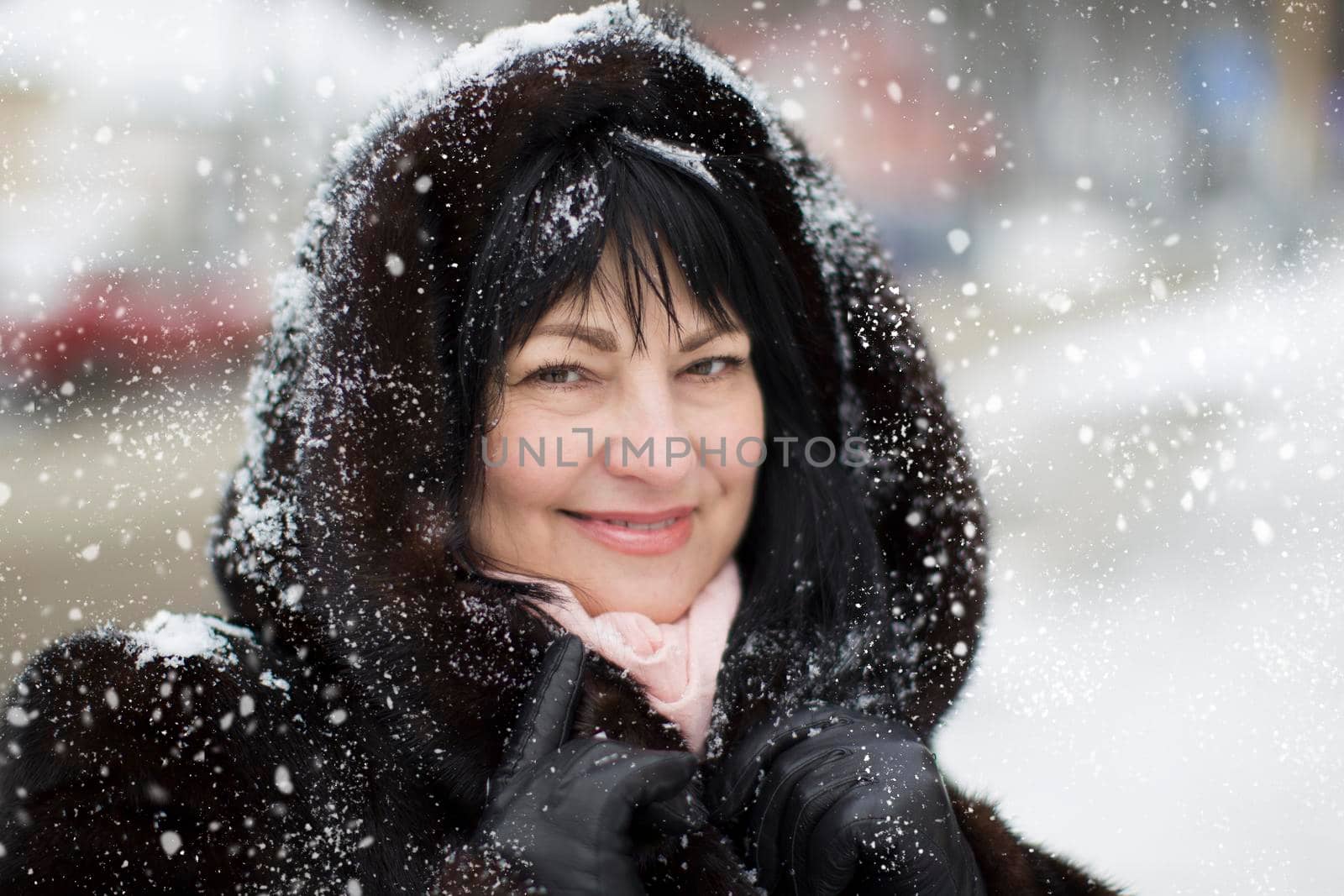 Elderly woman in a fur hood covered with snow