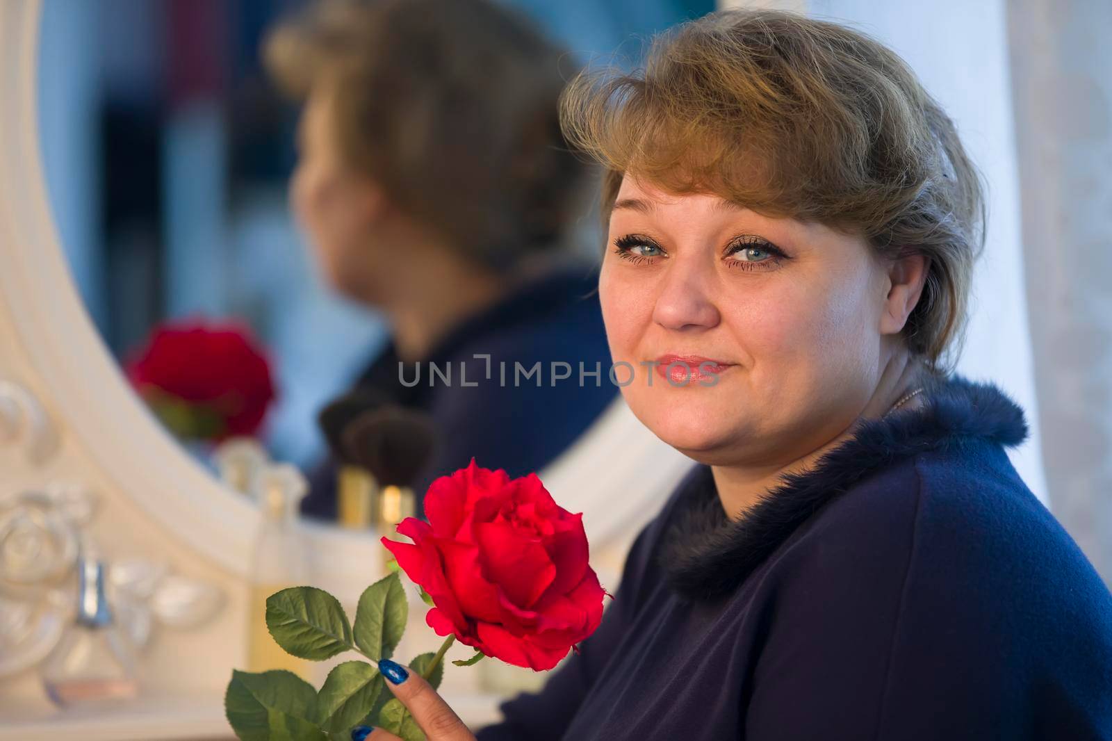 Portrait of an ordinary plump woman with a rose near a mirror