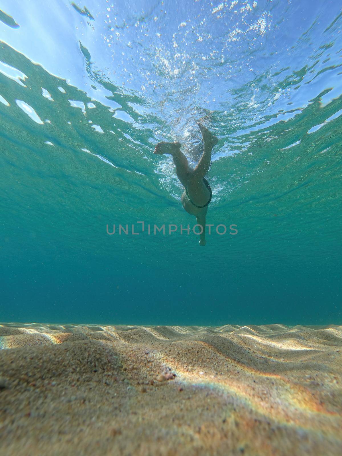 Sporty man swimming in a clear sea water in Spanish Costa Brava in summer by Digoarpi
