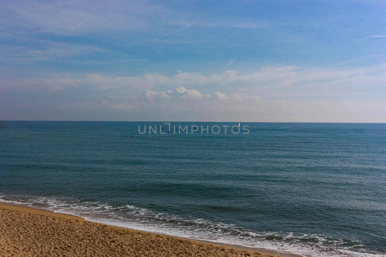 Barcelona beach in winter, with a calm sea and a cloudy blue sky