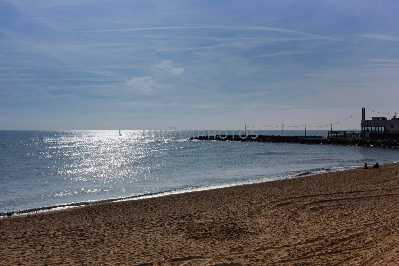 Barcelona beach in winter, with a calm sea and a cloudy blue sky